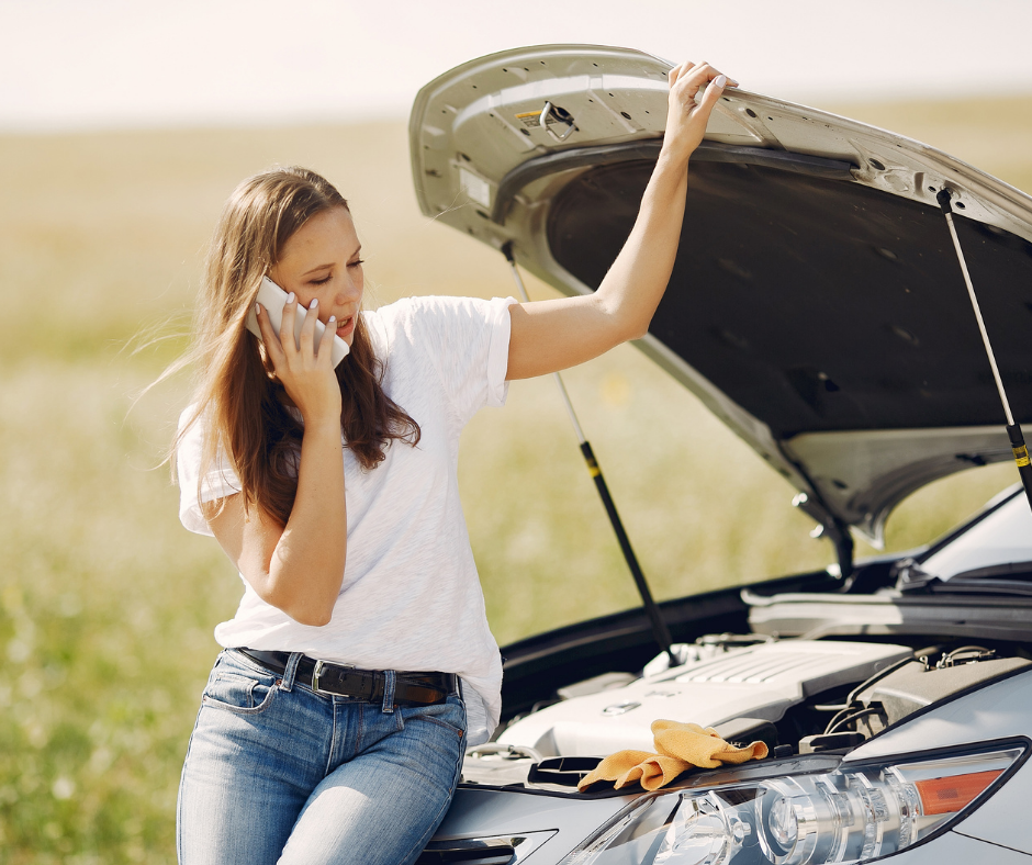 woman calling help on the phone beside a vehicle breakdown